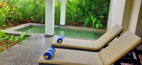 a pool with a bench in front of a house at Niraamaya Wellness Retreats Backwaters And Beyond Kumarakom in Kumarakom
