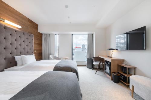 a hotel room with two beds and a television at THE KNOT SAPPORO in Sapporo