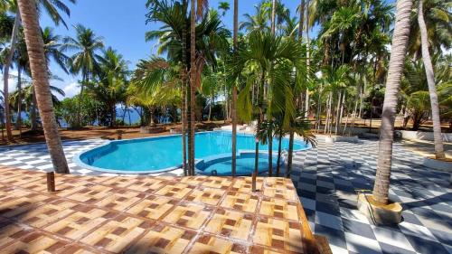 a swimming pool with palm trees and a resort at Adhvasaha Beach Spa Resort in Port Blair