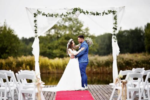 a bride and groom standing under an altar at their wedding at Hotel Farma Vysoká in Chrastava