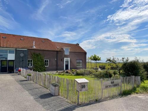 une maison avec une clôture devant elle dans l'établissement B&B Bouwmanshoeve, à Burgh-Haamstede