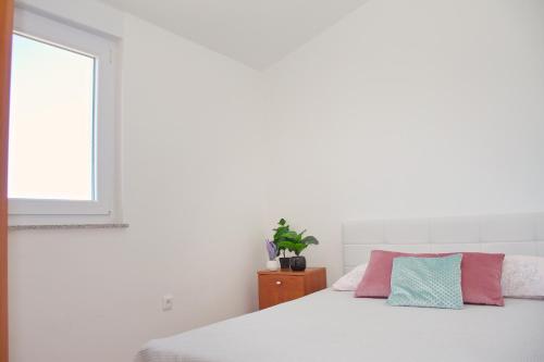 a white bedroom with a bed and a window at Summer Fun Apartment in Novalja