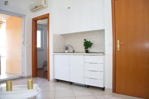 a white kitchen with a sink and a toilet at Summer Fun Apartment in Novalja