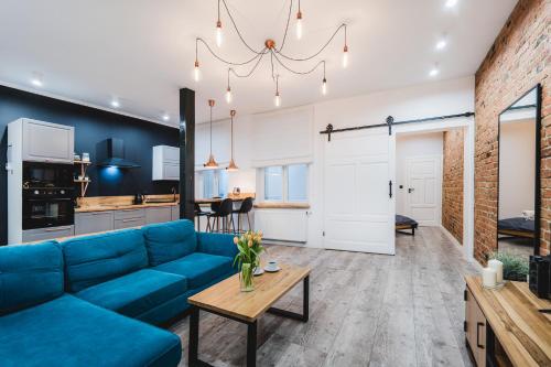 Una sala de estar con un sofá azul y una mesa. en Modern Apartments Toruń 2 Stare Miasto-Centrum, en Toruń