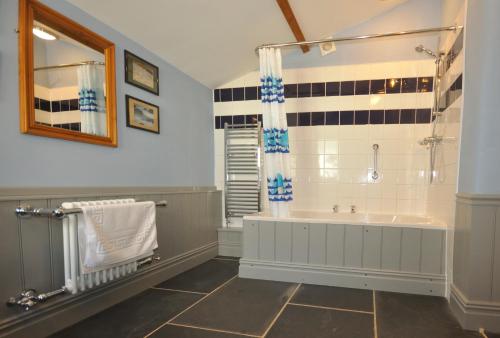 a bathroom with a tub and a shower at Granary at Trewerry Cottages - Away from it all, close to everywhere in Newquay