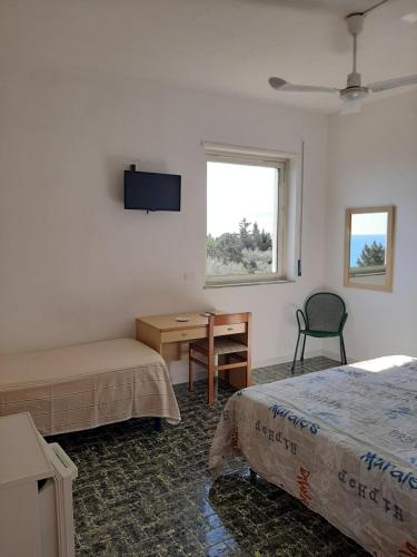 a bedroom with two beds and a desk and a window at Hotel Conca d'Oro in Stalettì
