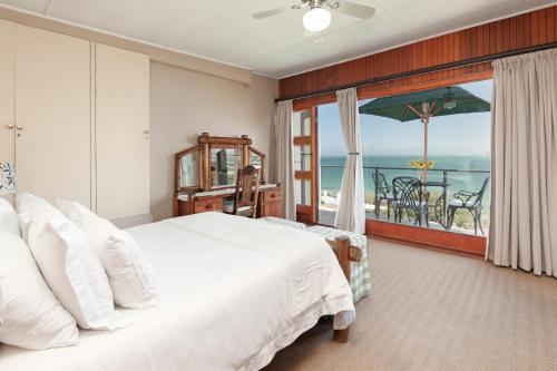 a bedroom with a bed and a view of the ocean at 18 On Kloof Guest House in Gordonʼs Bay