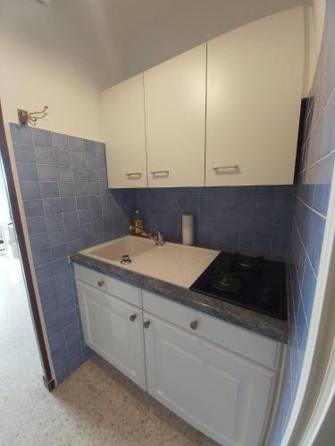 - une cuisine avec un évier, des placards blancs et du carrelage bleu dans l'établissement Studio Cap d'Agde le Môle, au Cap d'Agde