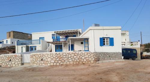 Casa blanca con ventanas azules y pared de piedra. en Seaside Residence Kiki Prassa,Kimolos en Kímolos