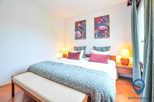 ein Schlafzimmer mit einem Bett und zwei Gemälden an der Wand in der Unterkunft Balaia Beach T2 com piscina in Albufeira