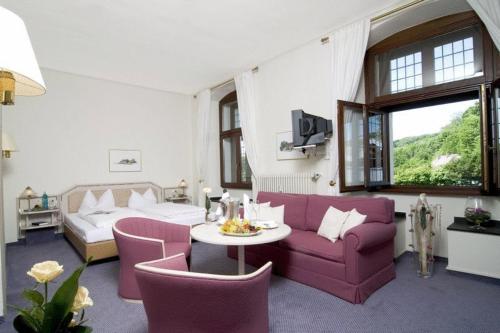 salon z fioletową kanapą i stołem w obiekcie Malteser Komturei Hotel / Restaurant w mieście Bergisch Gladbach