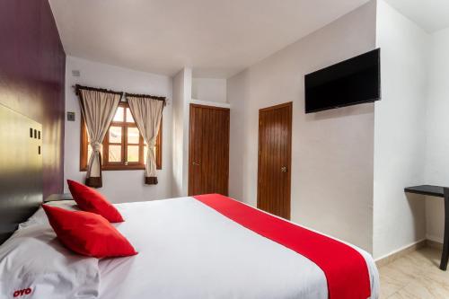 - une chambre avec un grand lit blanc et des oreillers rouges dans l'établissement OYO Hotel Emperadores Inn, Atlixco, à Atlixco