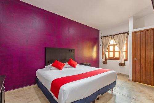 1 dormitorio con 1 cama grande y pared morada en OYO Hotel Emperadores Inn, Atlixco en Atlixco