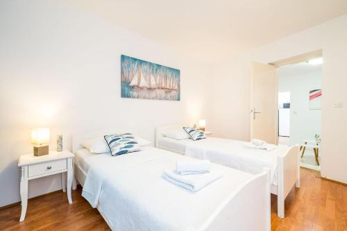 two beds in a room with white walls at Apartment Laura - Lapad in Dubrovnik