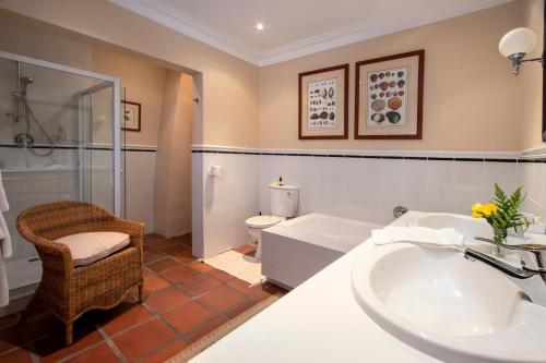 a bathroom with a sink and a tub and a toilet at La Fontaine Guest House Hermanus in Hermanus