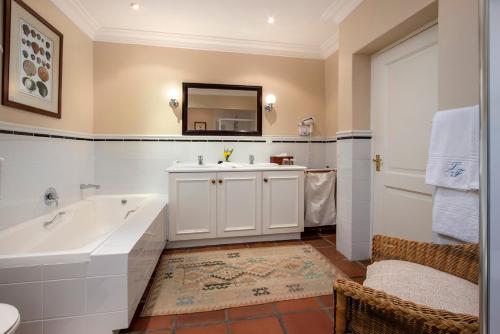 a bathroom with a tub and a sink and a mirror at La Fontaine Guest House Hermanus in Hermanus
