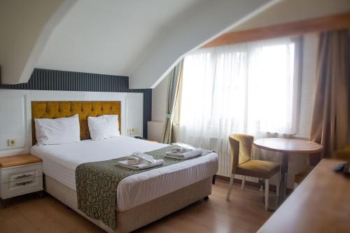 a hotel room with a bed and a table and window at Emirtimes Hotel Kadıköy in Istanbul