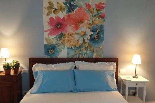 a bedroom with a bed with a painting on the wall at Appartamento - Lì de Là tra i fiori in Villafranca di Verona