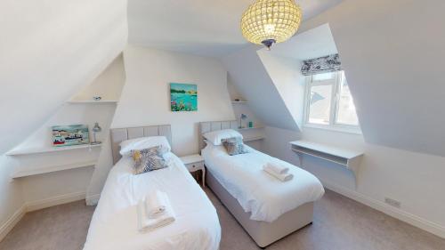 two beds in a attic room with white walls at Bethany Cottage in Sidmouth