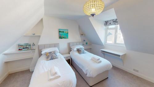 2 Betten in einem Dachzimmer mit weißen Wänden in der Unterkunft Bethany Cottage in Sidmouth