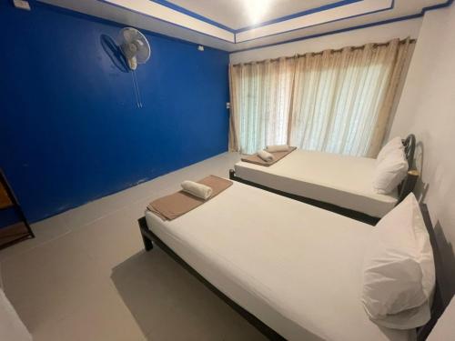 two beds in a room with a blue wall at Pranee Bungalow in Koh Tao