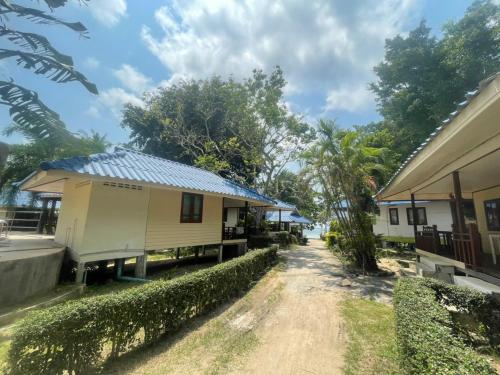 a house with a blue roof next to a dirt road at Pranee Bungalow in Koh Tao