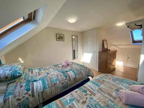 ein Schlafzimmer mit zwei Betten und einer Kommode in der Unterkunft Buttercup Cottage in Sidmouth