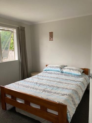 a bedroom with a bed with a blue comforter and a window at Comfortable Home Close to Airport in Christchurch