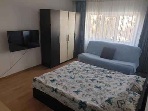 a bedroom with a bed and a couch and a television at Rozelor in Mangalia
