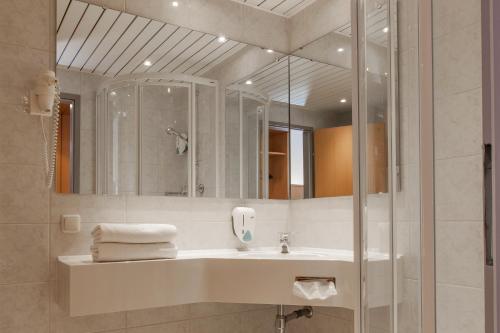 ein Bad mit einem Waschbecken und einem Spiegel in der Unterkunft Landzeit Motor-Hotel St. Valentin in Sankt Valentin