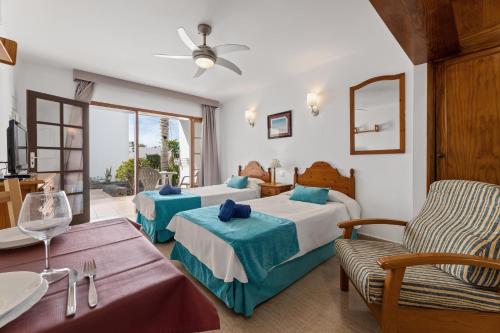 a hotel room with two beds and a table at Apartamentos las Lilas in Puerto del Carmen