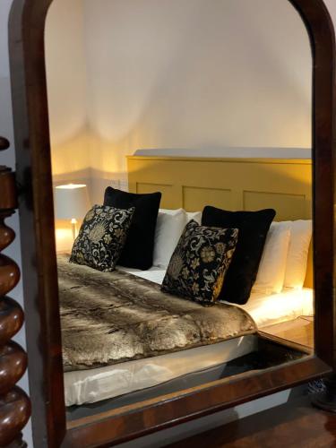 a mirror reflecting a bed with pillows on it at White Hart Hotel in Dorchester on Thames