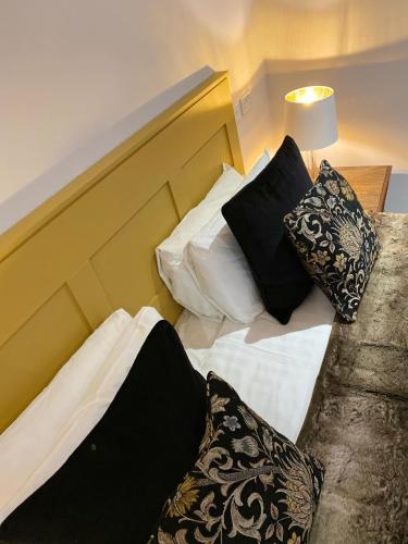 a bed with black and white pillows on it at White Hart Hotel in Dorchester on Thames