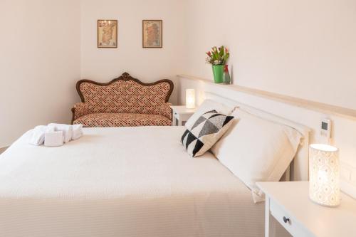 a white bedroom with a bed and a chair at Almasarda in Olbia