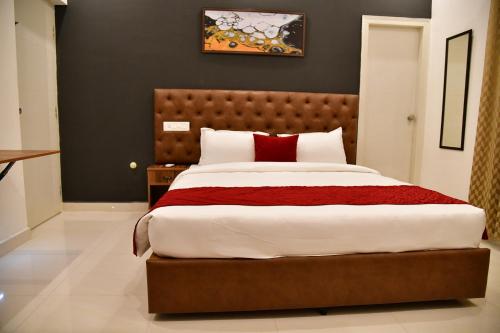 a bedroom with a large bed with red pillows at Xcel Luxury Hotel Apartments-Home Living Redefined in Mysore