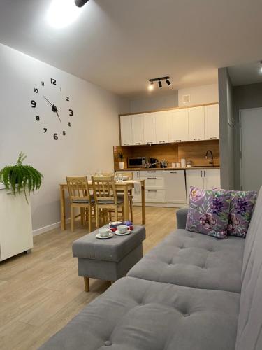 a living room with a couch and a table with a clock on the wall at Apartament Bieszczadzkie Widoki in Ustrzyki Dolne