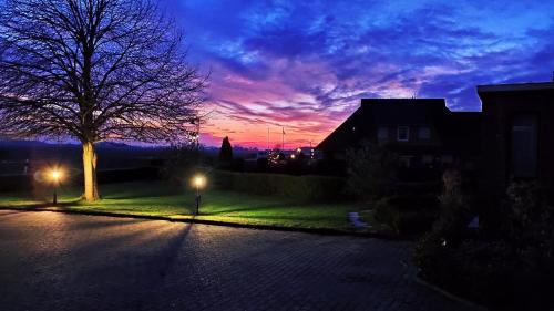 a sunset over a street with a tree and houses at Gästehaus Zur alten Post in Dornumersiel