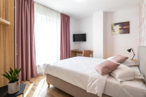 a bedroom with a large bed with pink curtains at TCI Apartments in Cluj-Napoca