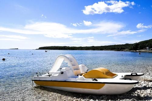 a boat sitting on the shore of a body of water at Durdica beautiful garden with fantastic sea and mountain views in Metajna