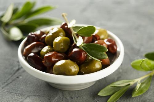 a bowl of olives with green leaves on a table at Durdica beautiful garden with fantastic sea and mountain views in Metajna