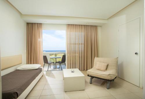 a bedroom with a bed and a chair and a table at Lindos White Hotel & Suites in Líndos