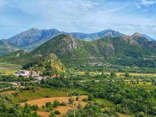 a small town on a hill with mountains in the background at Eco Villas Merak in Virpazar
