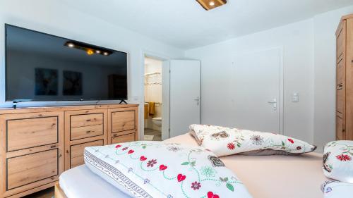 a bedroom with a flat screen tv and a bed with pillows at Appartements Bergwelt in Oetz