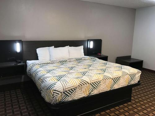 Studio 6 Suites Tupelo, MS في توبيلو: غرفة نوم بسرير كبير مع سريرين فرديين وطاولتين.