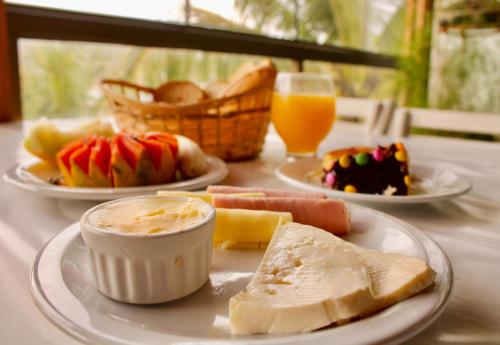 una tavola con piatti di cibo e un bicchiere di succo d'arancia di Pousada Casa da Praia ad Arraial do Cabo