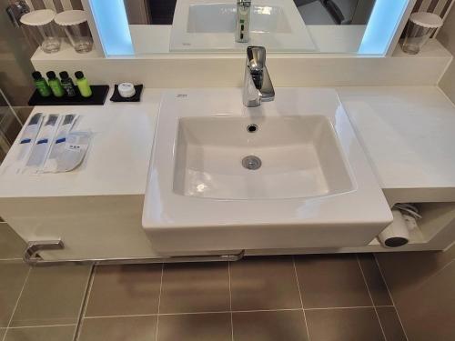 a white bathroom sink with a faucet on a counter at Hotel Tour Incheon Airport Hotel & Suites in Incheon