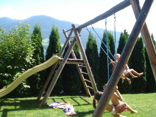 two children playing on a swing set in a yard at Huberhof Appzimmer in Feldthurns
