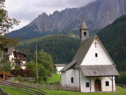 a small white church with a cross on the front at Huberhof Appzimmer in Feldthurns