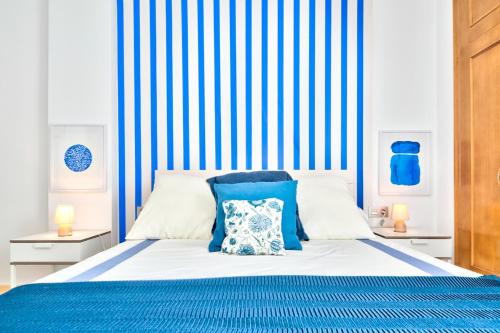 a bed with a blue and white striped wall at MalagadeVacaciones - Muriel in Málaga