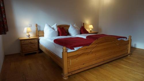 a bedroom with a large wooden bed with red pillows at Hölzlhof in Amerang